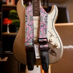 Electric guitar with a bright, abstract-pattern strap draped over its neck and white pickguard. ขายราคาพิเศษ