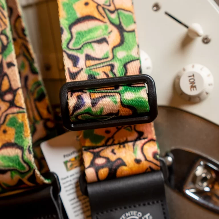 Colorful patterned guitar strap with a black buckle and a nearby tone knob on a guitar. ขายราคาพิเศษ