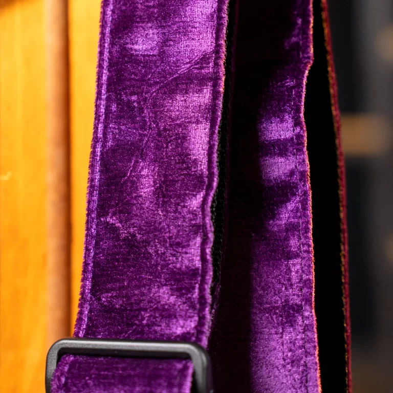 Close-up of a purple velvet strap with a black plastic buckle against an orange background. ขายราคาพิเศษ