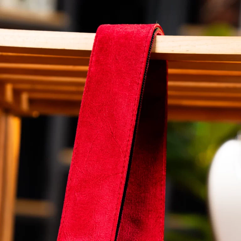 Bright red velvet sash draped over a light wooden beam, with a dark edge visible along the side. ขายราคาพิเศษ