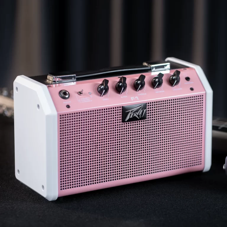 Pink portable guitar amplifier with white side panels, black top handle, and control knobs on top (Gain, Bass, Treble) over a perforated front grille with a Peavey logo. ขายราคาพิเศษ