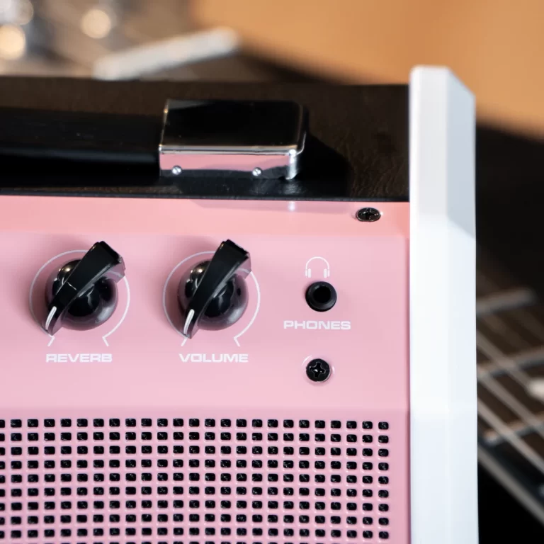 Pink guitar amplifier front panel with Reverb and Volume knobs, headphone jack, and perforated speaker grille ขายราคาพิเศษ