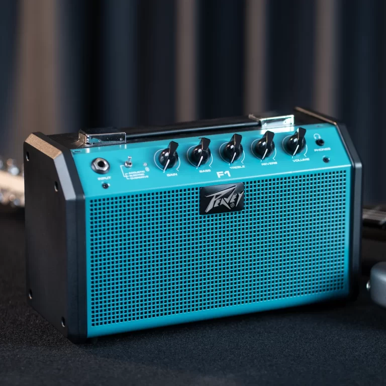 Turquoise Peavey guitar amplifier with control knobs for gain, bass, treble, reverb, and volume, and a perforated front grille. ขายราคาพิเศษ