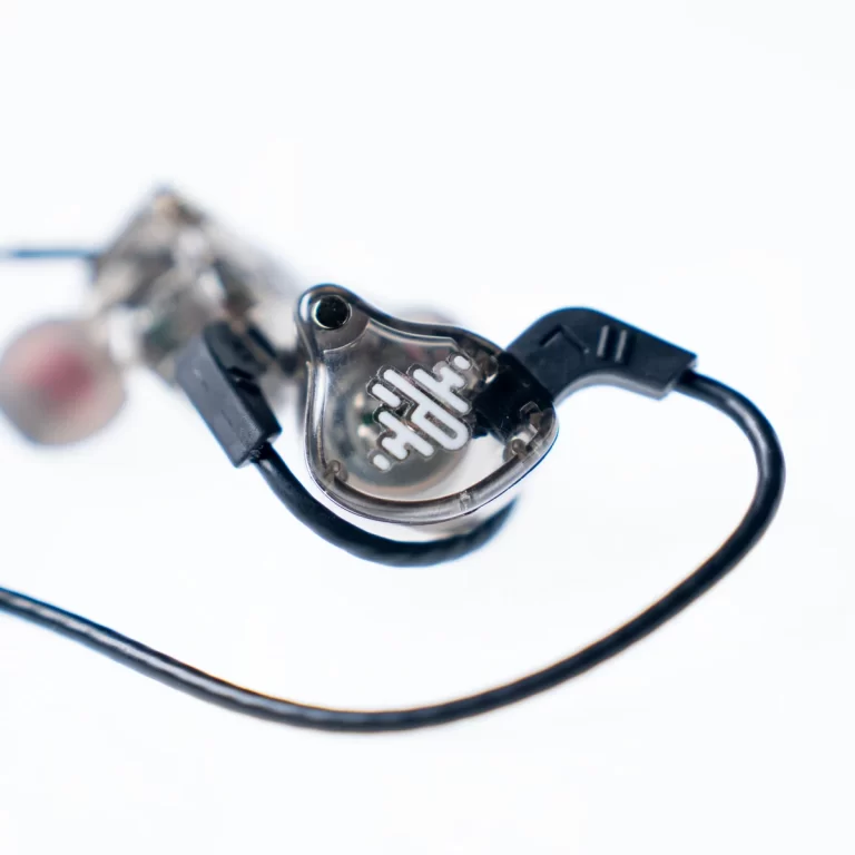 Close-up of a transparent in-ear monitor earphone with a black cable on a white background. ขายราคาพิเศษ