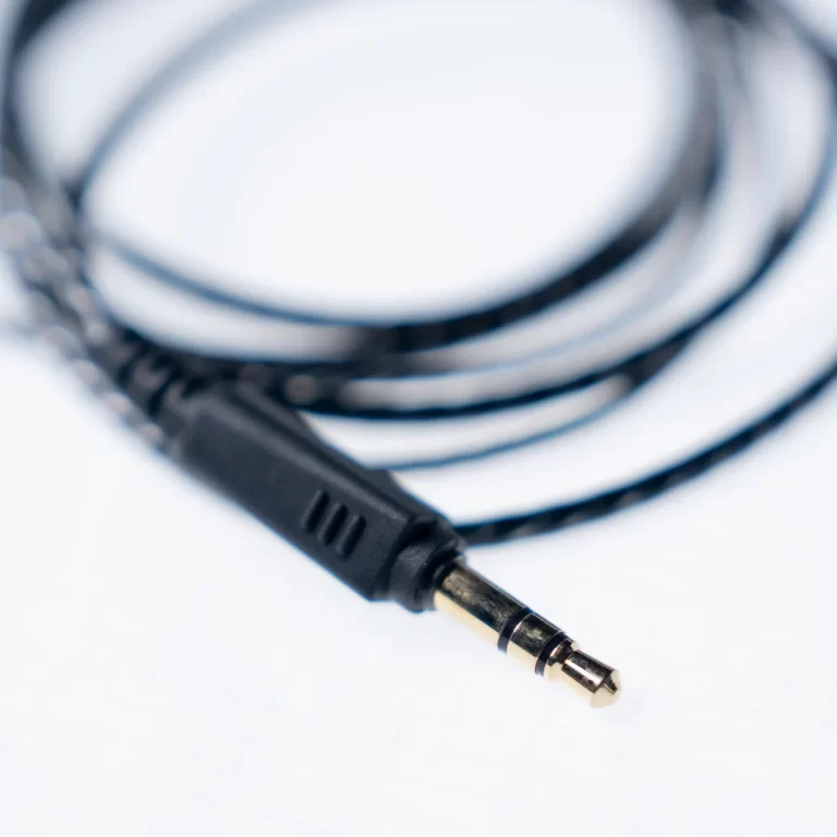 Close-up of a black 3.5mm stereo audio plug with a coiled cord on a light background ขายราคาพิเศษ