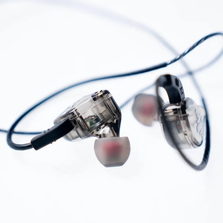 Close-up of clear in-ear monitor earbuds with white silicone tips and a tangled blue cable on a white background, angled for detail. ขายราคาพิเศษ