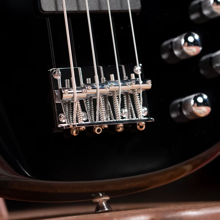 Close-up of a chrome electric guitar bridge and tremolo saddles on a glossy black body. ขายราคาพิเศษ