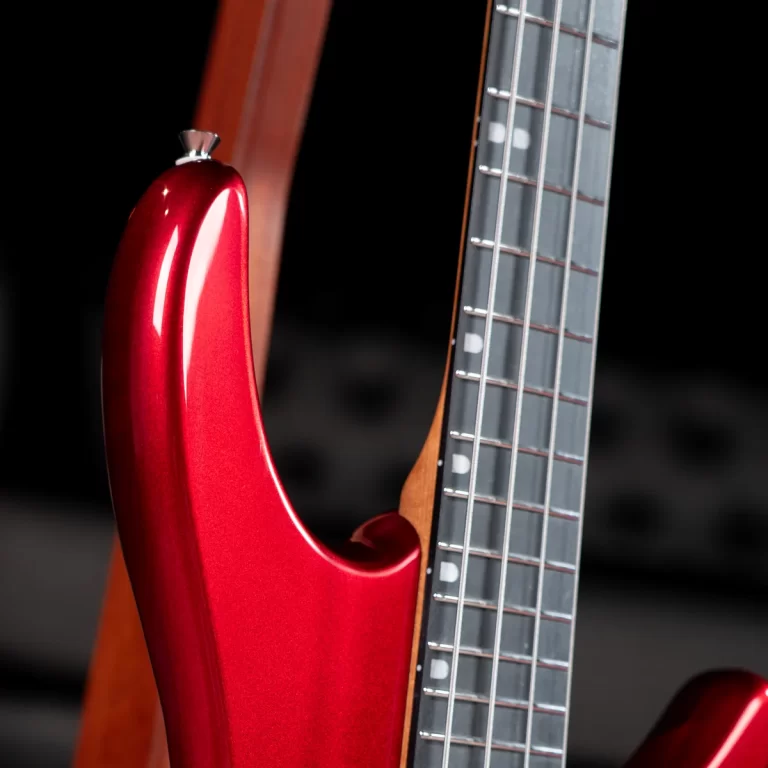 Close-up of a glossy red electric guitar body with a dark fretboard on the right against a black background. ขายราคาพิเศษ
