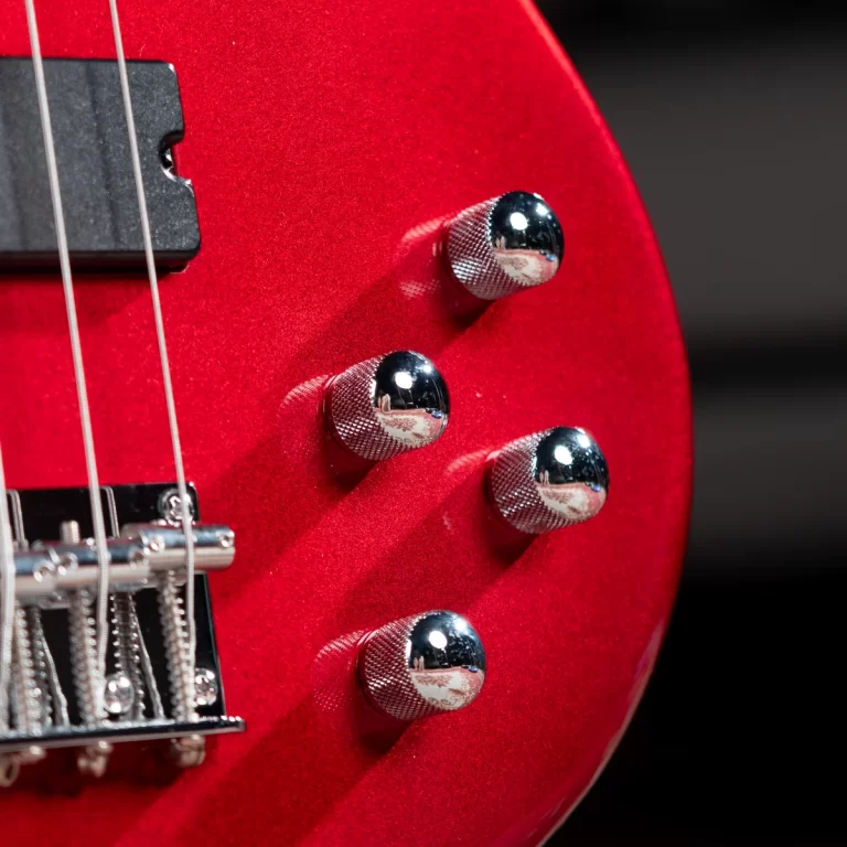 Close-up of a red electric guitar body with chrome knurled control knobs and part of the bridge and strings visible in the frame. ขายราคาพิเศษ