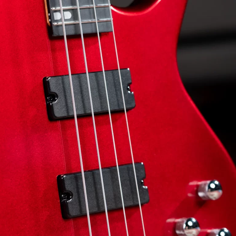 Close-up of a red electric guitar body showing two black pickups and metal strings running over them. ขายราคาพิเศษ