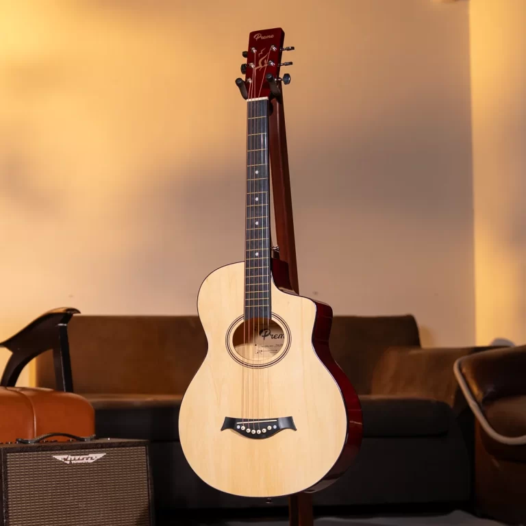 An acoustic guitar on a stand in a warmly lit living room, with a small amplifier and couch visible in the background. ขายราคาพิเศษ