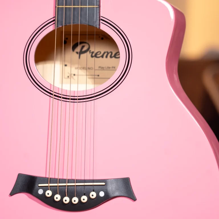 Close-up of a pink acoustic guitar body with strings, sound hole, and black bridge. ขายราคาพิเศษ