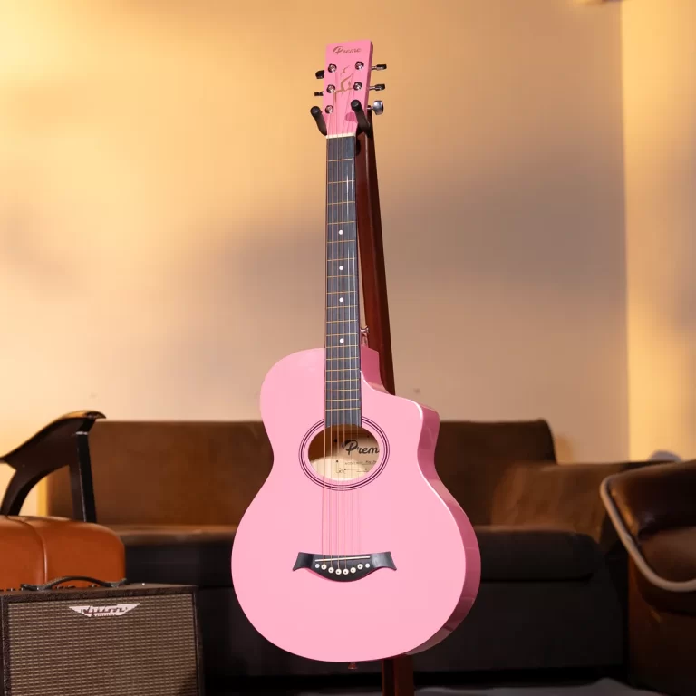 Pink acoustic guitar on a stand in a cozy living room, with a brown sofa and an amp nearby. ขายราคาพิเศษ