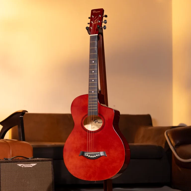 Red acoustic guitar on a stand in a living room, with a small amplifier nearby on the floor. ขายราคาพิเศษ