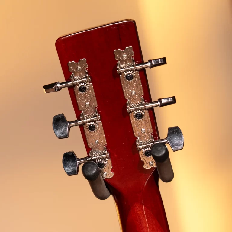 Close-up of a guitar headstock with ornate gold tuners and tuning pegs against a warm background. ขายราคาพิเศษ