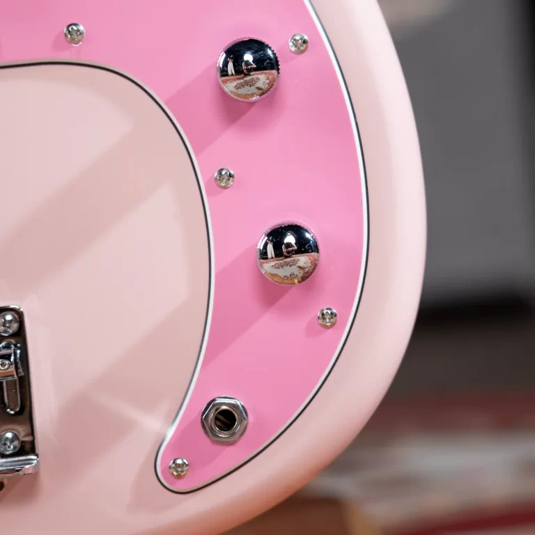 Close-up of a pink electric guitar body with chrome control knobs and an output jack. ขายราคาพิเศษ