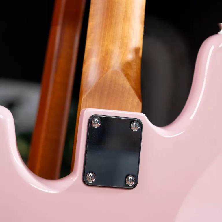 Close-up of a pink electric guitar body where the neck meets the body, showing a chrome neck plate with four screws. ขายราคาพิเศษ