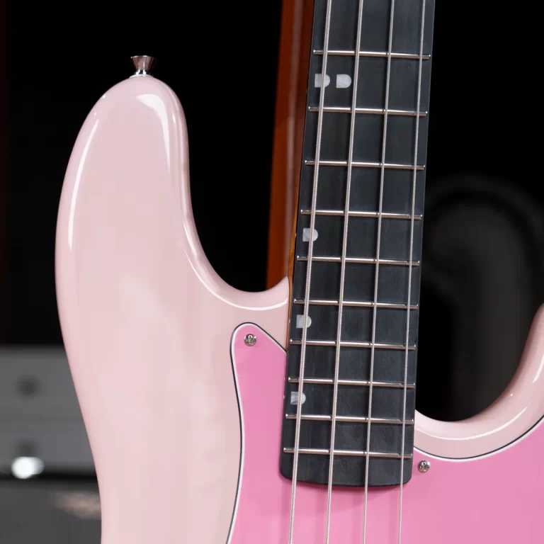 Close-up of a pink electric guitar body with a dark fretboard and metal strings visible on the neck, including a pink pickguard area near the strings. ขายราคาพิเศษ