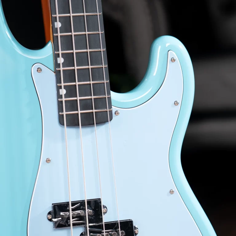 Close-up of a light-blue electric bass guitar body with strings and a white pickguard against a dark background. ขายราคาพิเศษ