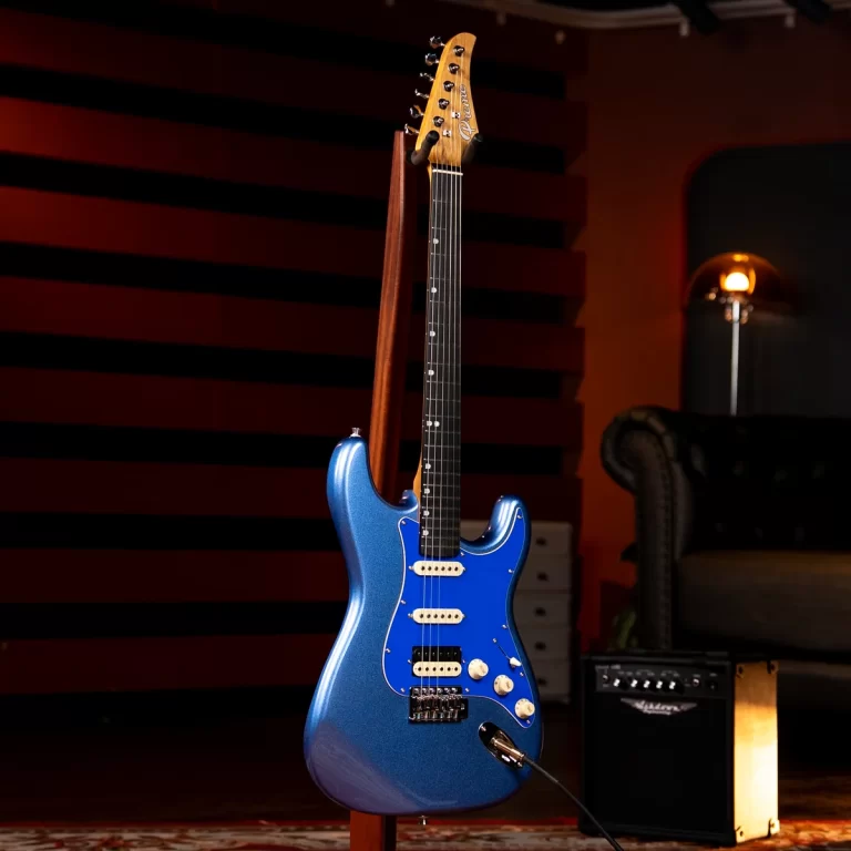 Blue metallic Stratocaster-style electric guitar on a stand in a recording space with a small amplifier nearby. ขายราคาพิเศษ
