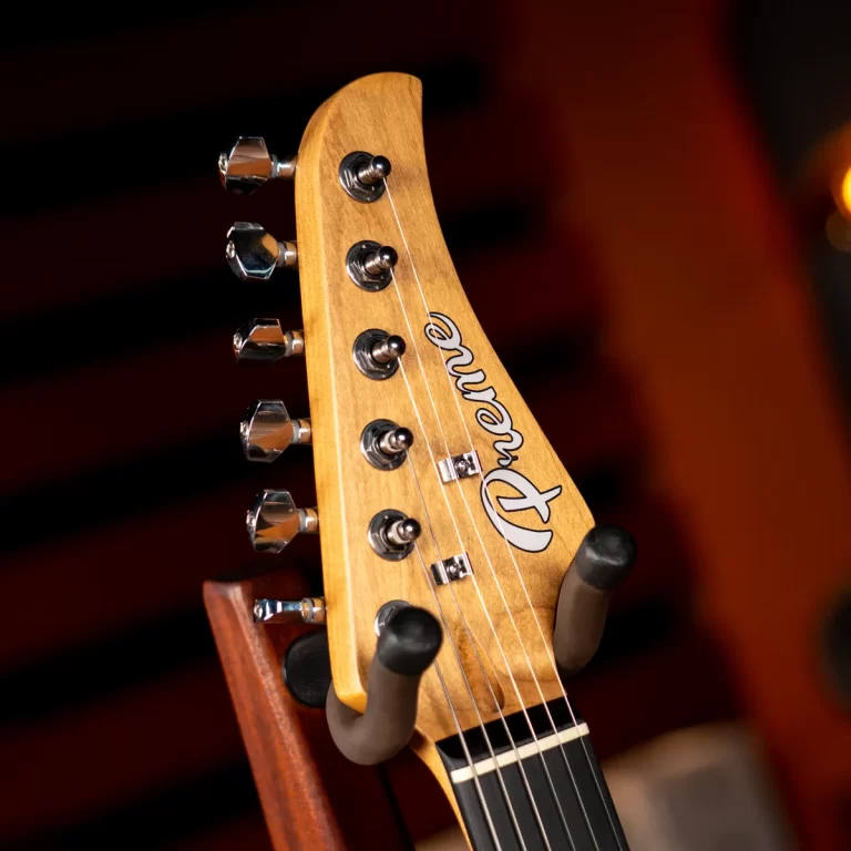Close-up of a wooden guitar headstock with six chrome tuning pegs, strings, and the Fender logo visible. ขายราคาพิเศษ