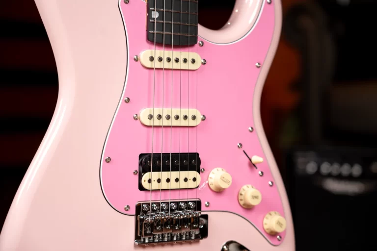 Close-up of a pink electric guitar showing cream pickups and a chrome bridge. ขายราคาพิเศษ