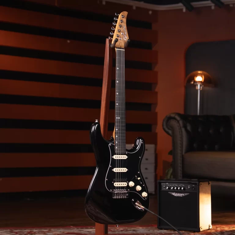 Black solid-body electric guitar on a stand in a recording studio, with an orange and brown acoustic wall backdrop and a small amplifier nearby. ขายราคาพิเศษ