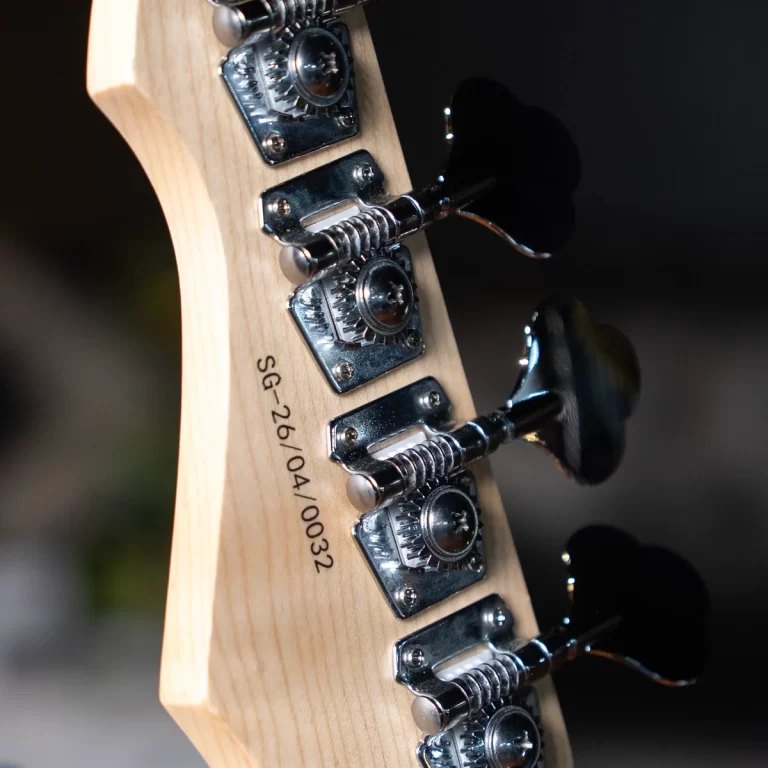 Close-up of a guitar headstock with chrome tuning pegs and wood grain, showing the serial number SG-26/04/0032. ขายราคาพิเศษ