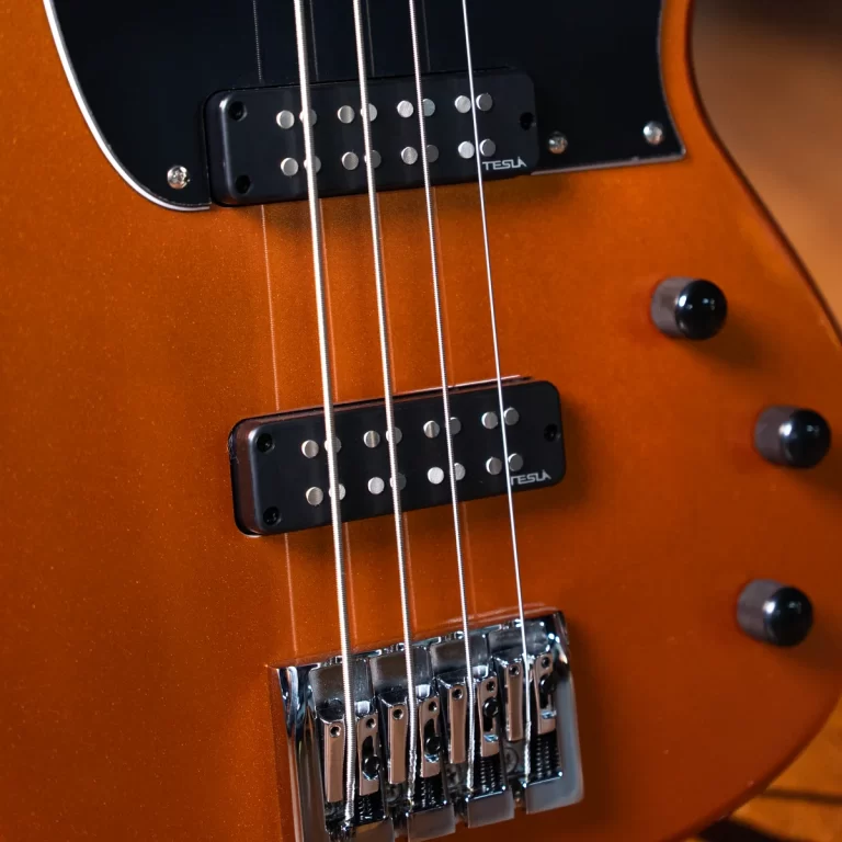 Close-up of an orange electric guitar body with two black Tesla humbucker pickups, strings, and a chrome bridge and knobs. ขายราคาพิเศษ