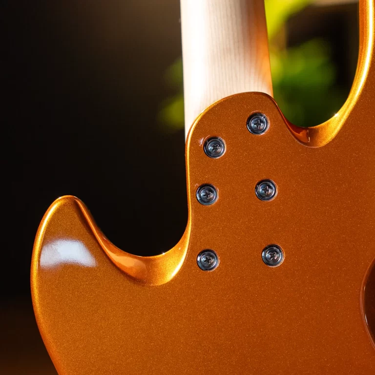 Close-up of an orange metallic electric guitar body with multiple screws securing the neck area against a dark background. ขายราคาพิเศษ