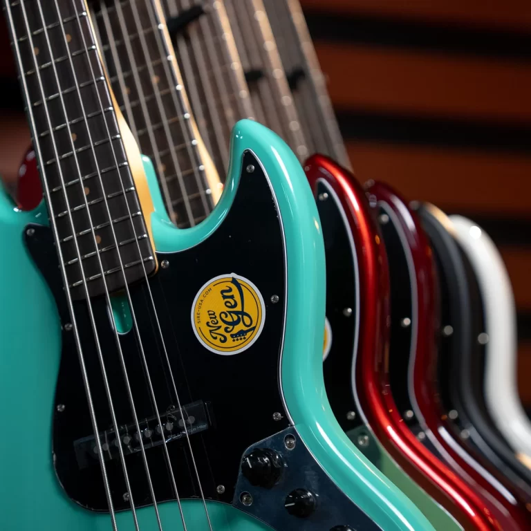 Row of colorful electric guitars on display, turquoise guitar in focus with a yellow circular sticker on the pickguard. ขายราคาพิเศษ
