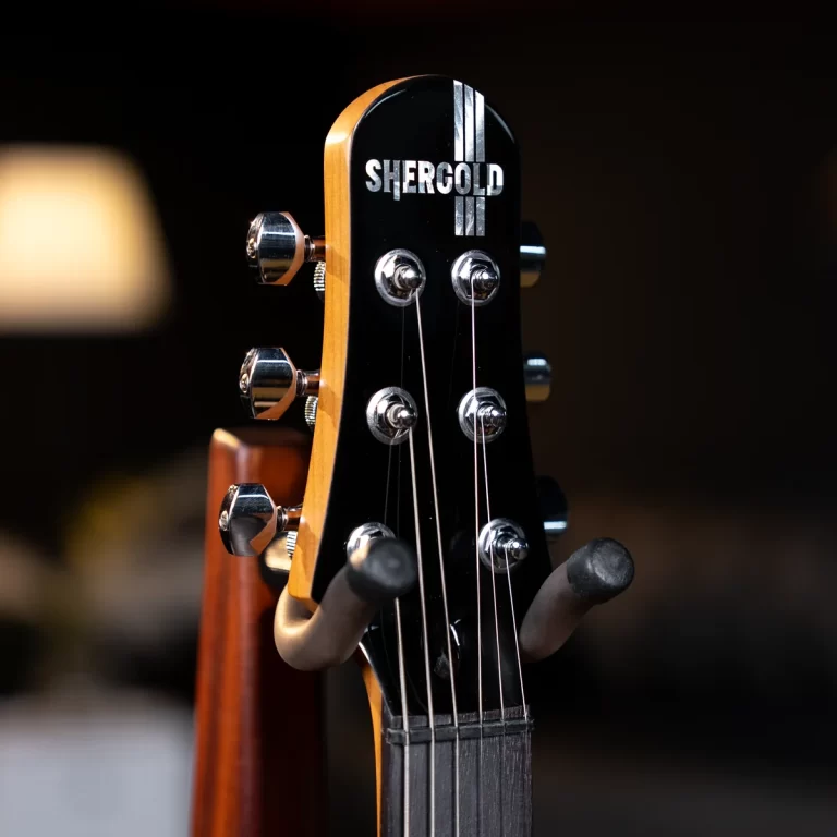 Close-up of a guitar headstock with six tuning pegs and strings, black finish, brand SHERGOLD visible ขายราคาพิเศษ