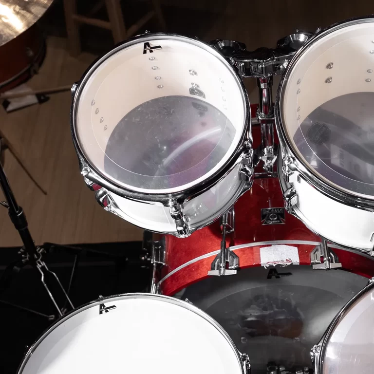 Close-up of a red drum kit with white drum heads and chrome hardware, focusing on mounted toms and bass drum. ขายราคาพิเศษ