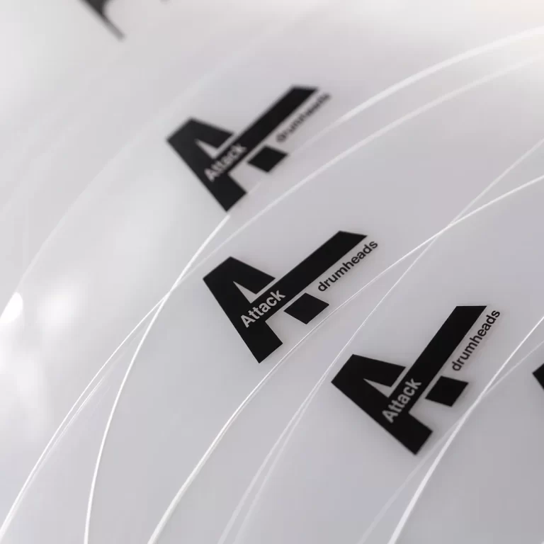 Close-up of white drumheads with a black Attack logo and the word drumheads visible. ขายราคาพิเศษ
