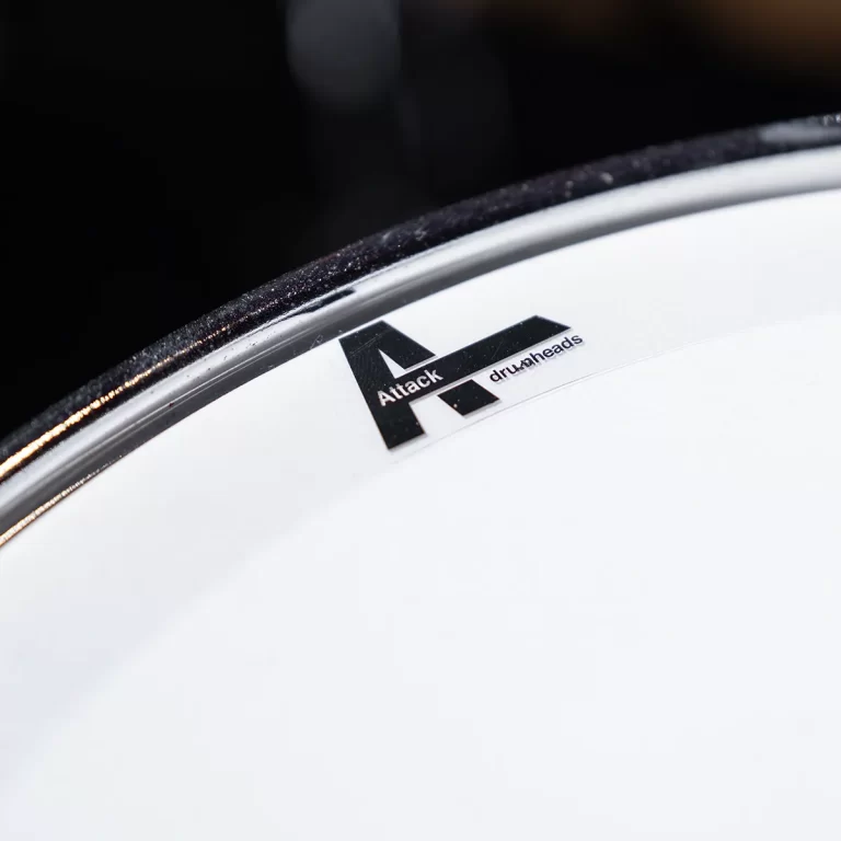 Close-up of a white drum head displaying the黑 Attack drumheads logo near the rim. ขายราคาพิเศษ