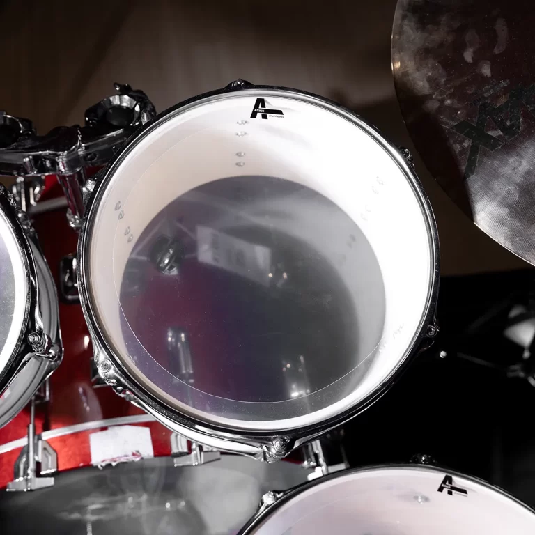 Close-up of a drum tom with a chrome rim, red shell, and a cymbal to the right partly visible. ขายราคาพิเศษ