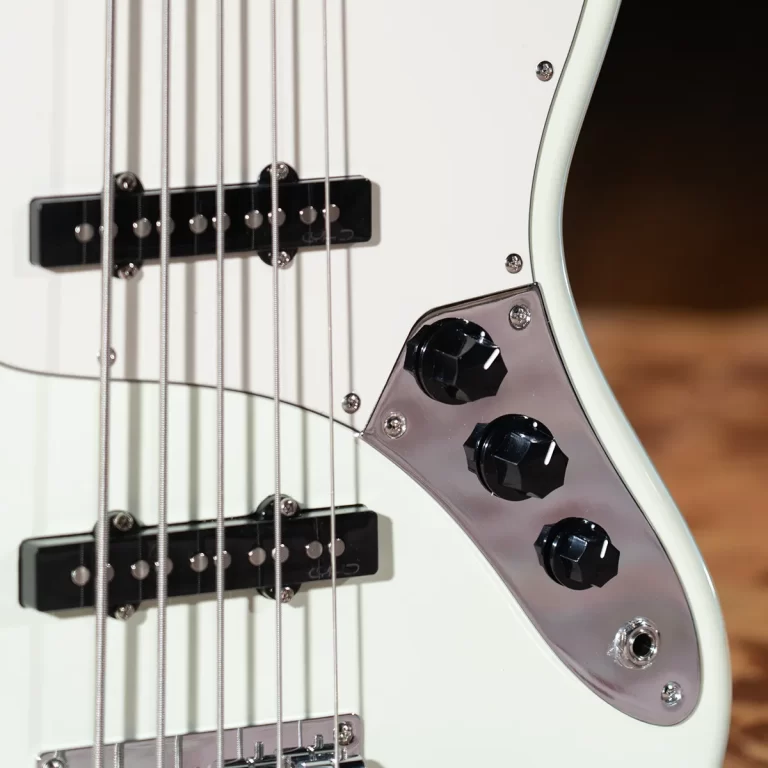 Close-up of a white electric guitar body with two black pickups, six strings, and a chrome control plate featuring three black knobs. ขายราคาพิเศษ