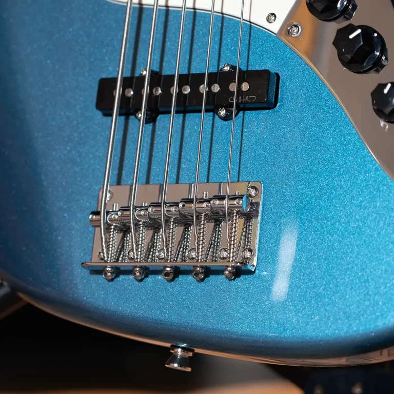 Close-up of a blue metallic electric guitar body with a black pickup, chrome bridge saddles, and six steel strings. ขายราคาพิเศษ
