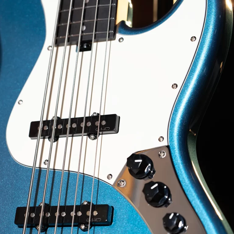 Close-up of a metallic blue electric bass guitar body with strings, pickups, and control knobs visible ขายราคาพิเศษ