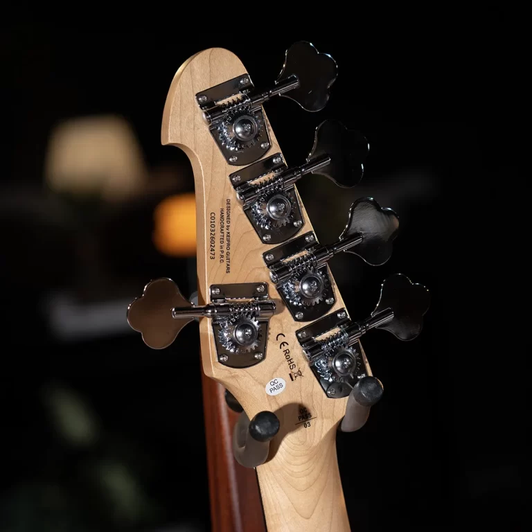 Close-up of a wooden guitar headstock with chrome tuning pegs against a dark background, showing detailed gear mechanisms. ขายราคาพิเศษ