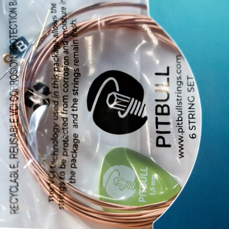 Copper guitar strings coiled on packaging labeled PITBULL 6-STRING SET, with a black logo and a green pick graphic on the package. ขายราคาพิเศษ