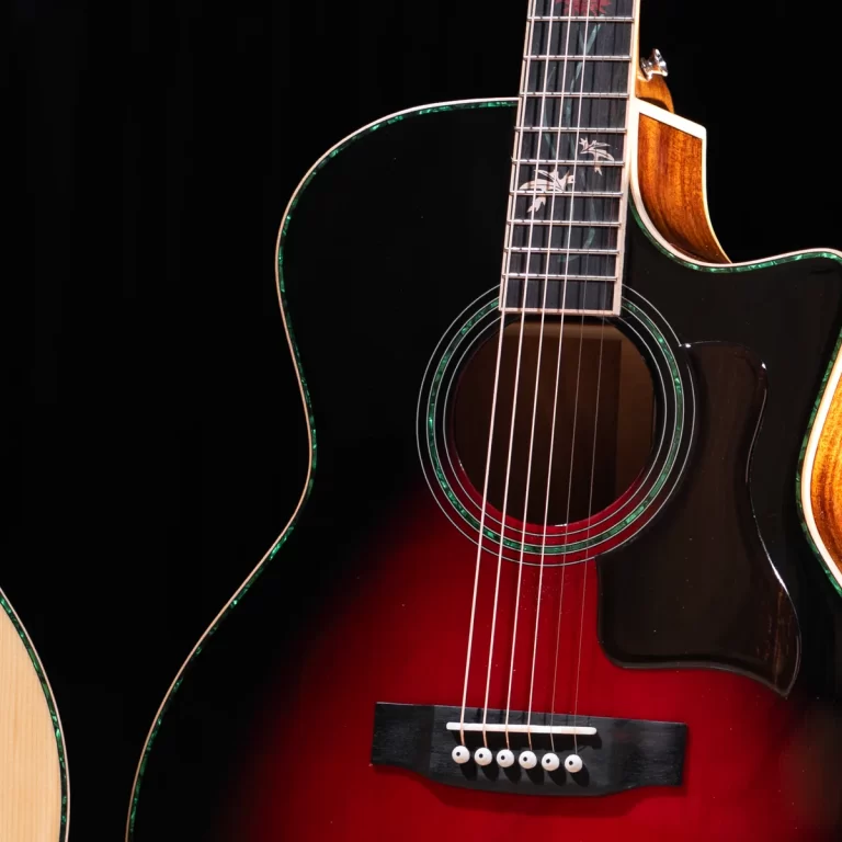 Close-up of a sunburst acoustic guitar with a black body, red gradient at the bottom, and green binding around the sound hole, showing strings and fretboard detail. ขายราคาพิเศษ