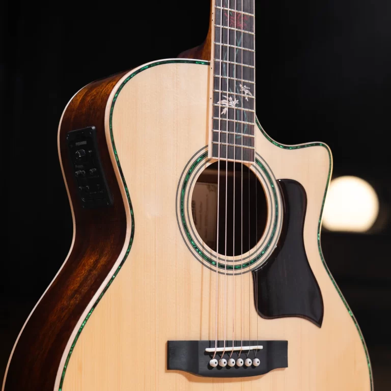 Close-up of an acoustic guitar body with natural wood top, green binding, soundhole, and six strings visible. The cutaway and pickguard are also shown. ขายราคาพิเศษ
