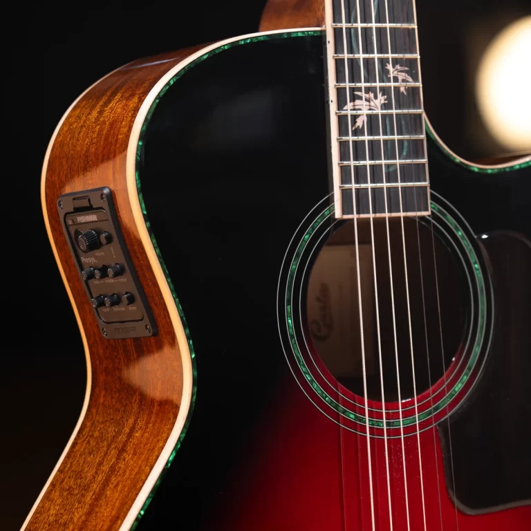 Close-up of a glossy black and sunburst acoustic guitar with green binding, showing soundhole and strings. Built-in pickup controls are on the side panel. ขายราคาพิเศษ