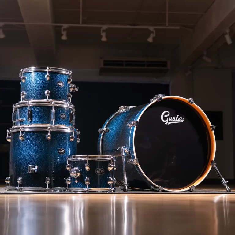 Blue glitter drum kit with floor tom, rack toms, snare, and a large bass drum on a wooden floor in a studio setting. ขายราคาพิเศษ