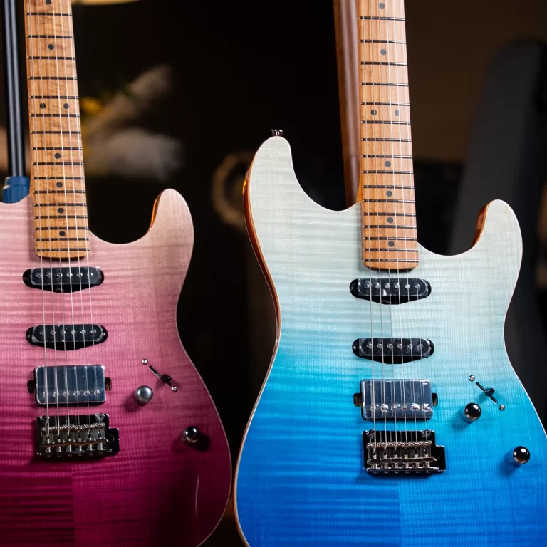 Two electric guitars in pink and blue gradient finishes standing side by side, necks with maple fretboards visible. ขายราคาพิเศษ