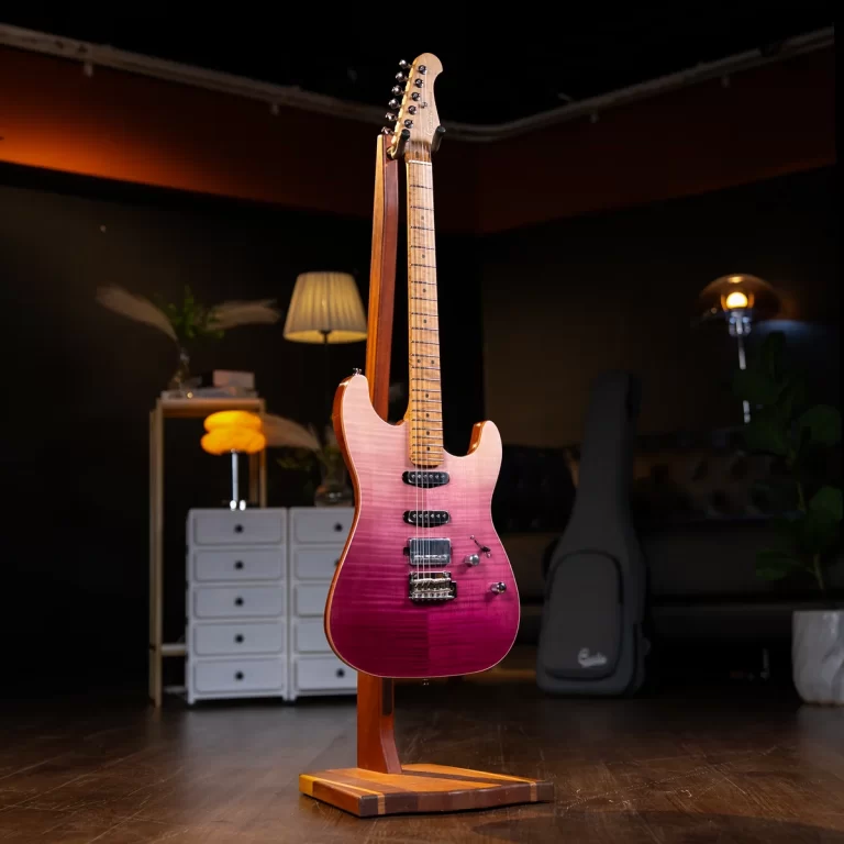 Pink-to-purple electric guitar on a wooden stand in a dimly lit room with a white drawer chest in the background. ขายราคาพิเศษ