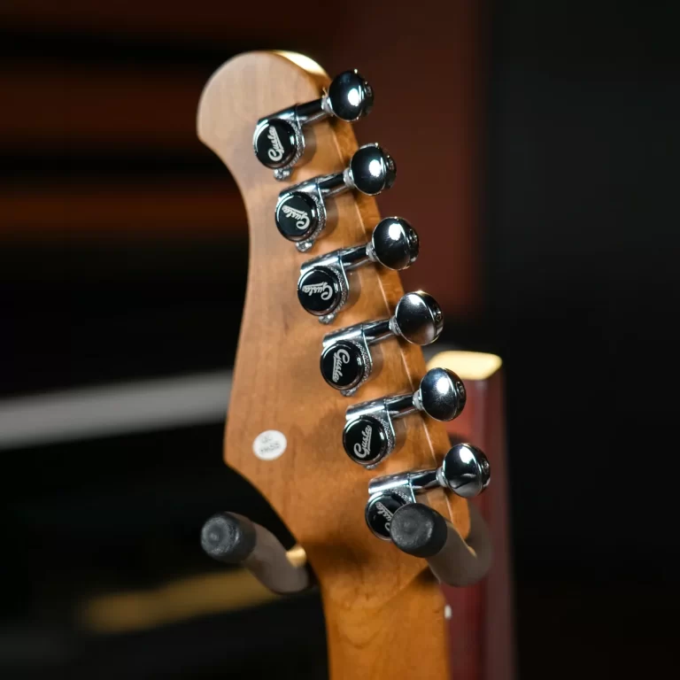 Close-up of a guitar headstock with six chrome tuning pegs and a brown neck. ขายราคาพิเศษ
