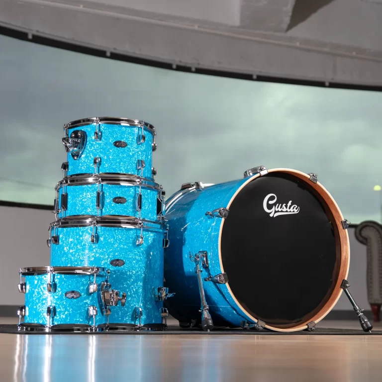 Blue sparkle drum kit with a bass drum labeled 'Gusta' on a showroom floor. ขายราคาพิเศษ