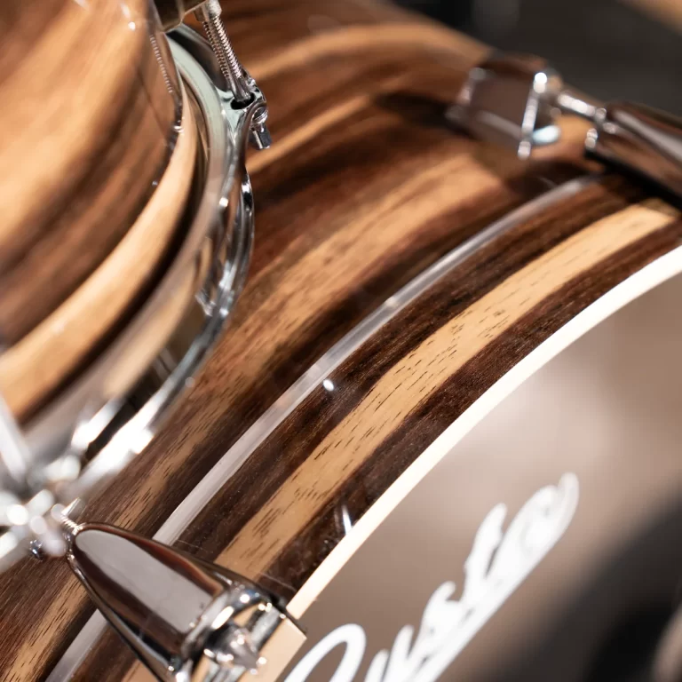 Close-up of a wooden drum with striped brown finish and chrome hardware, showing lugs and rim details. ขายราคาพิเศษ